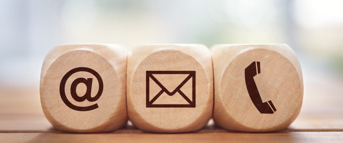 Contact us concept with wood block and symbols at, e-mail address and phone